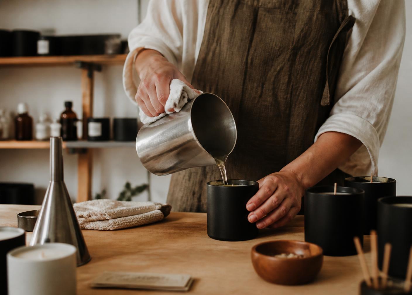 Wax being poured by hand into a dark candle vessel